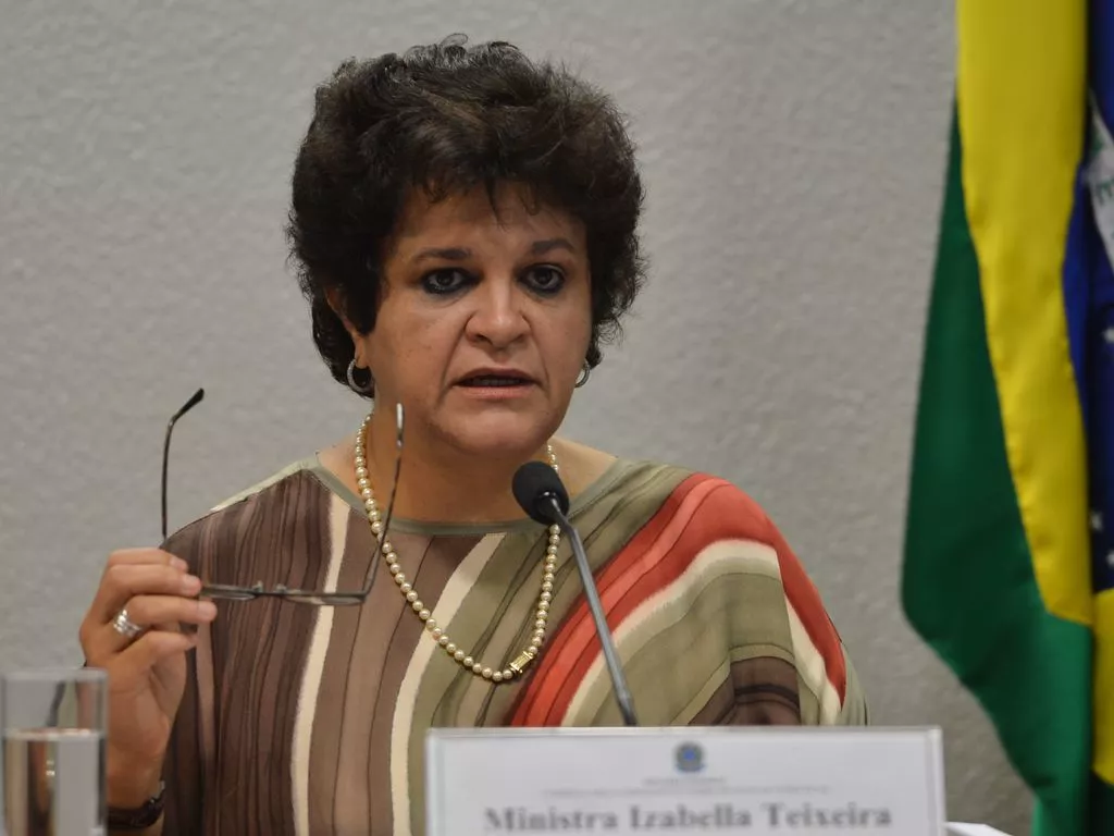 Brasil tem “papel estratégico de segurança climática”, diz ex-ministra Izabella Teixeira 50 Ex-ministra do Meio Ambiente, Izabella Teixeira durante fala na Comissão Mista Permanente sobre Mudanças Climáticas; Teixeira é uma mulher branca com olhos e cabelos castanhos escuro; ela veste uma camiseta colorida em tons de marrom, branco e verde e segura o óculos na mão direita